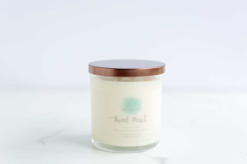 Elegant white candle jar with copper lid photographed on marble countertop.
