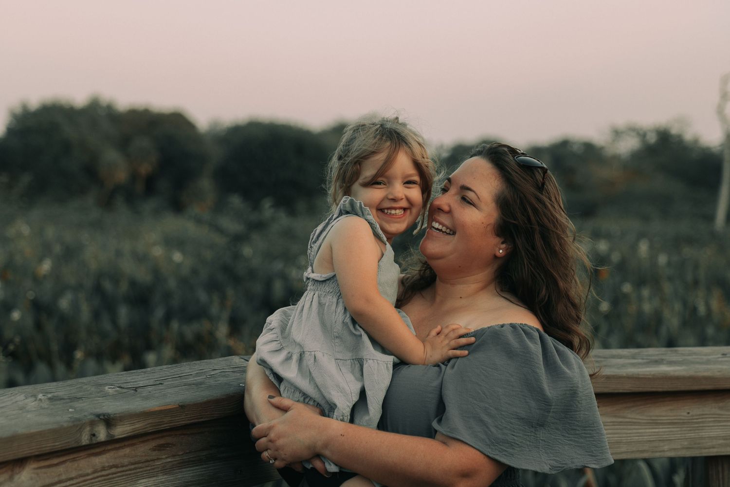 A joyful moment shared between two people on a wooden deck at sunset.