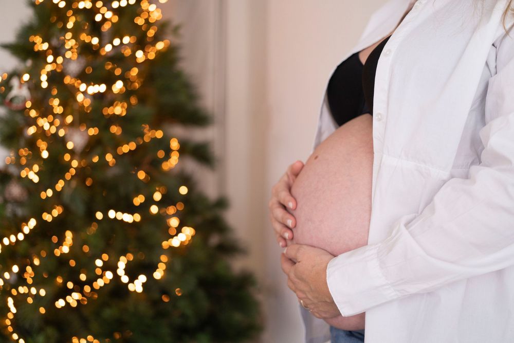 mani sulla pancia, gravidanza e albero di natale con le lucine gialle, mamma in dolce attesa a Natale, maternità a Natale, donna gravidanza