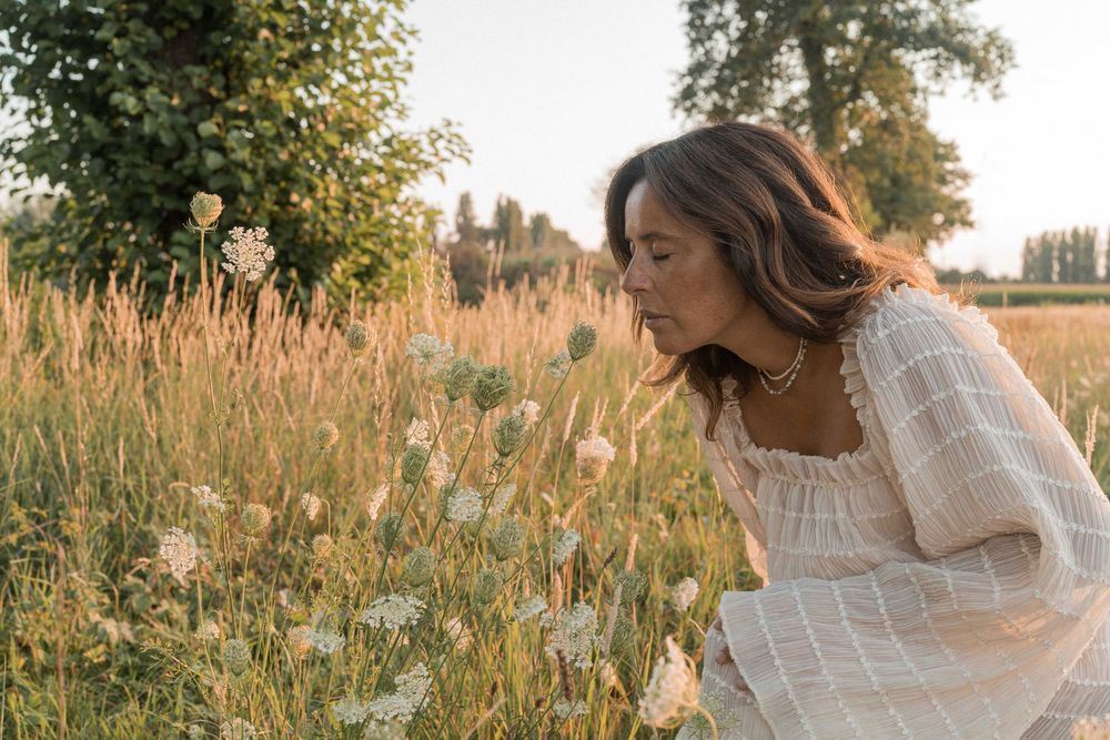 donna incinta annusa dei fiori in campagna al tramonto