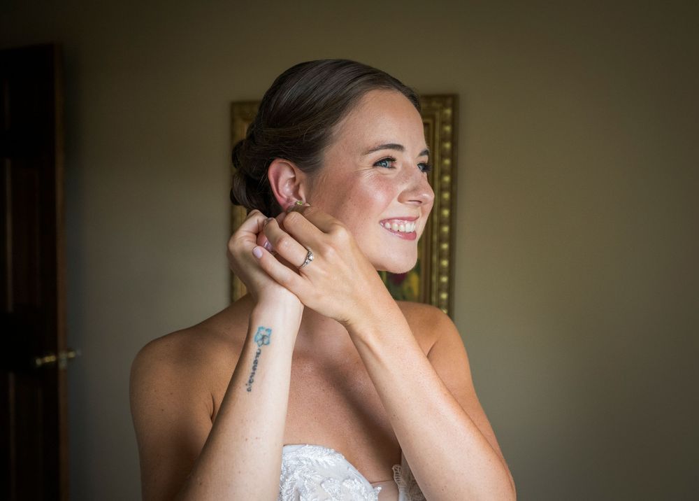 Elegant bridal preparation moment in soft natural window light.