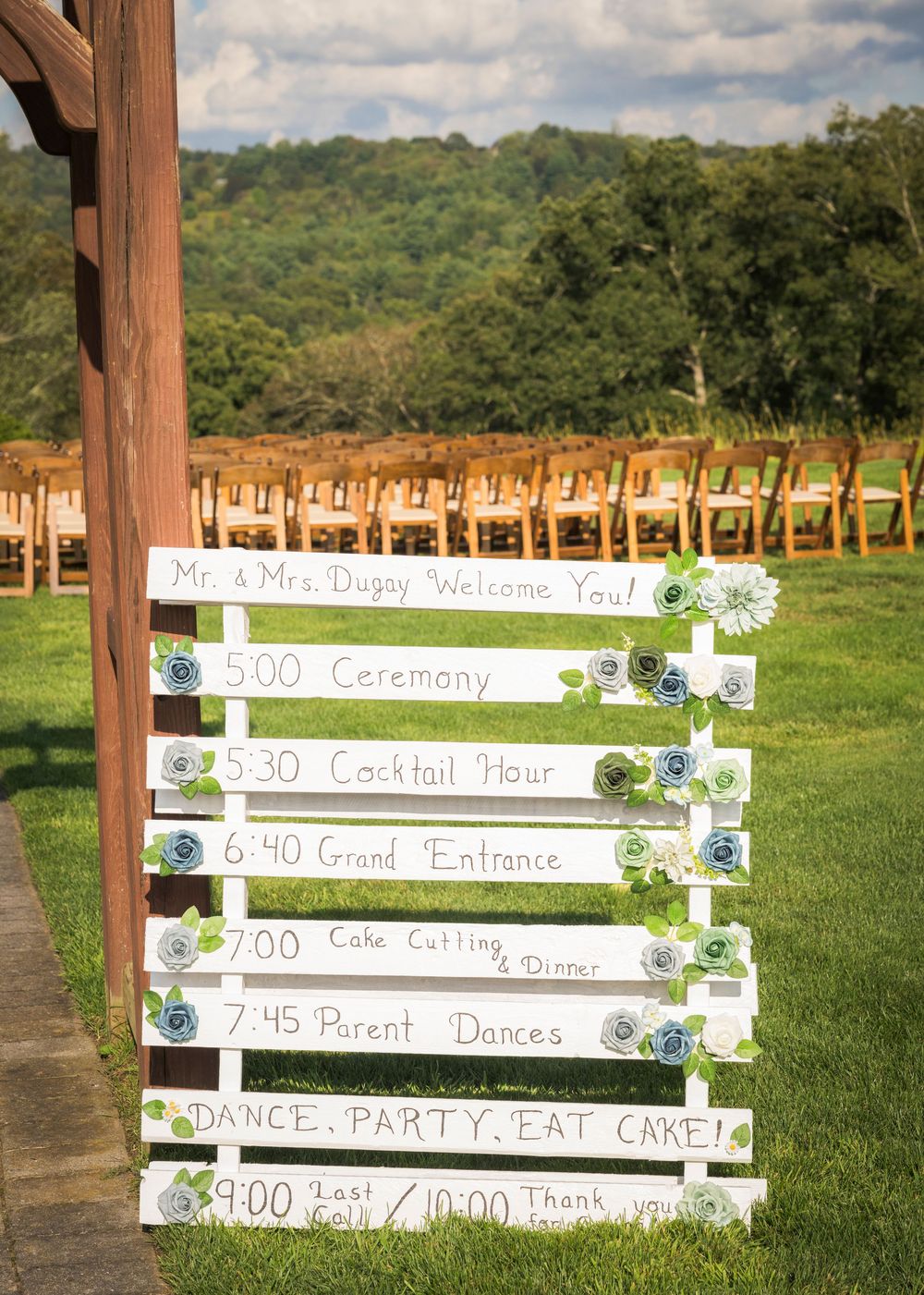 White wooden fence displays wedding ceremony timeline and schedule details.
