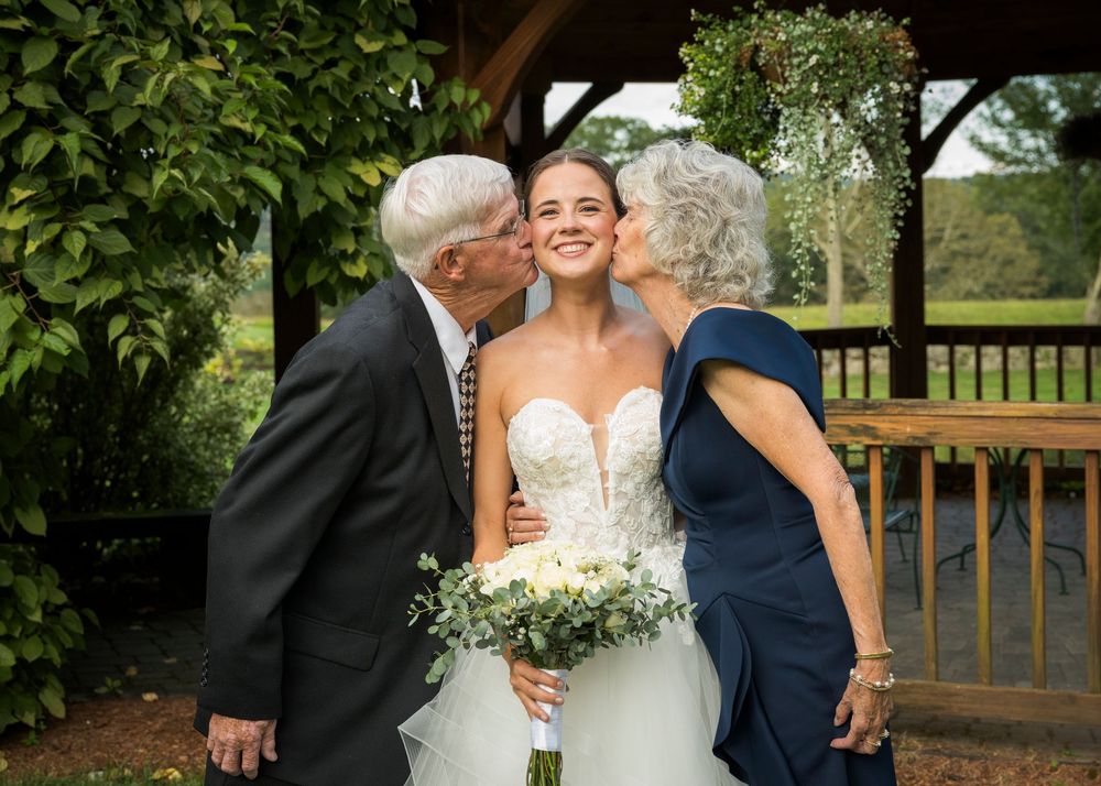 Wedding party poses for outdoor photos on a rustic wooden deck.