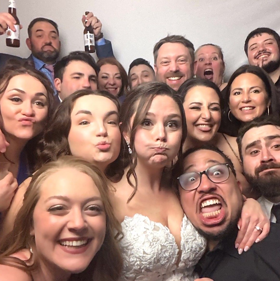 A festive wedding party takes a silly group selfie with funny expressions.