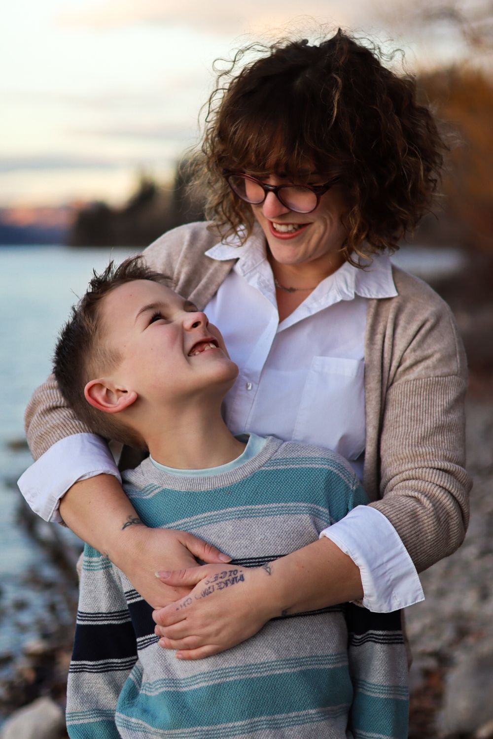 Joyful moment shared between parent and child by lakeside at dusk.