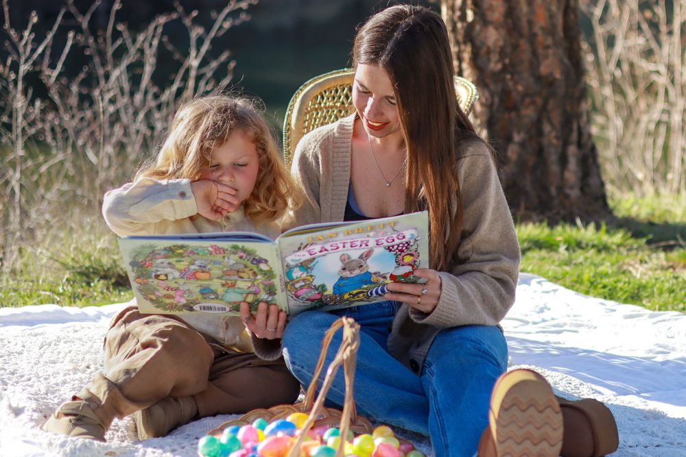 Reading a book together on a cozy blanket outdoors during a sunny afternoon.