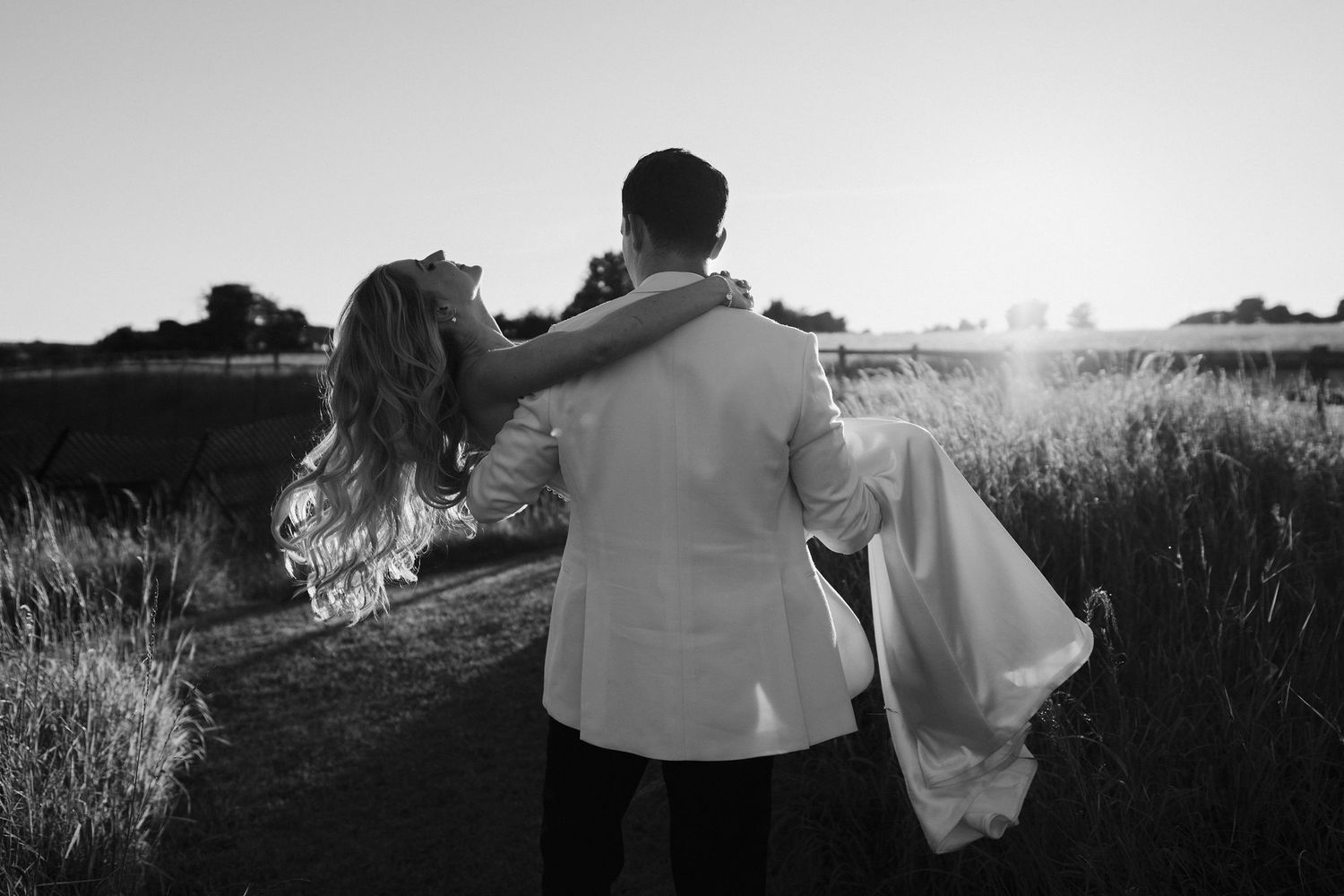 bride throwing her head back while groom lifts and spins her during golden hour at hamswell house in bath