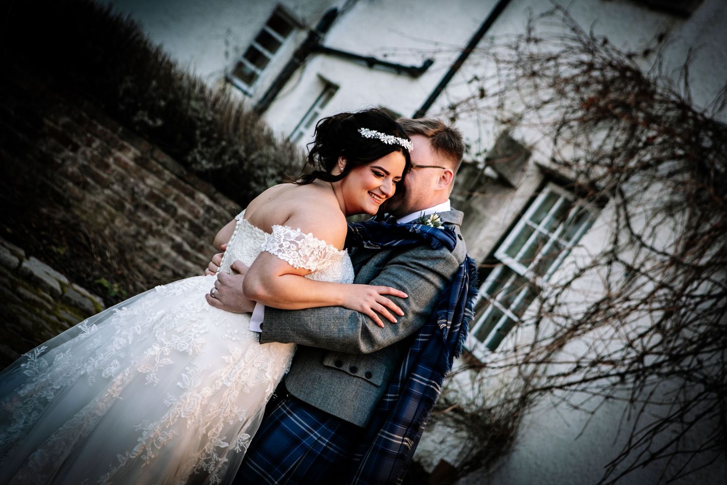 A couple in wedding attire embraces romantically against a rustic stone wall background in a series of intimate poses.