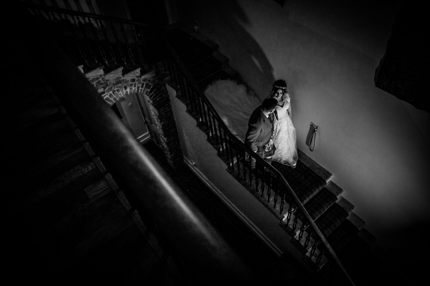 Dramatic black and white silhouettes of people walking on a curved path with dark shadows and vignetting.