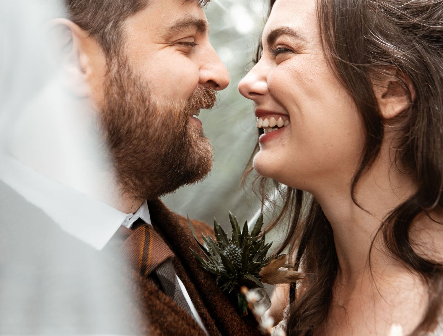 A loving couple gazes at each other in close up view with soft smiles and warm expressions.