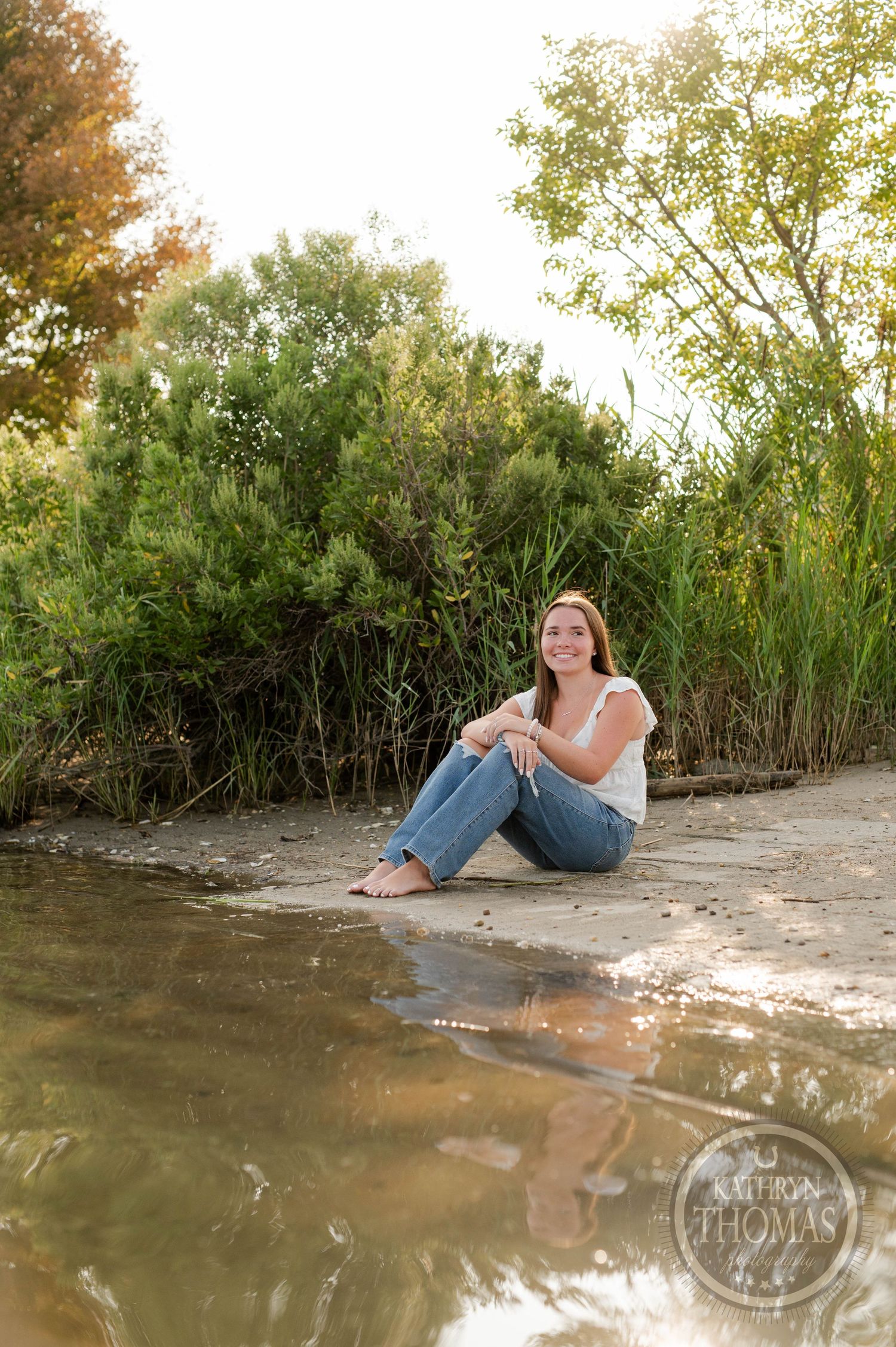 A waterside portrait with natural reflections and green foliage during golden hour.
