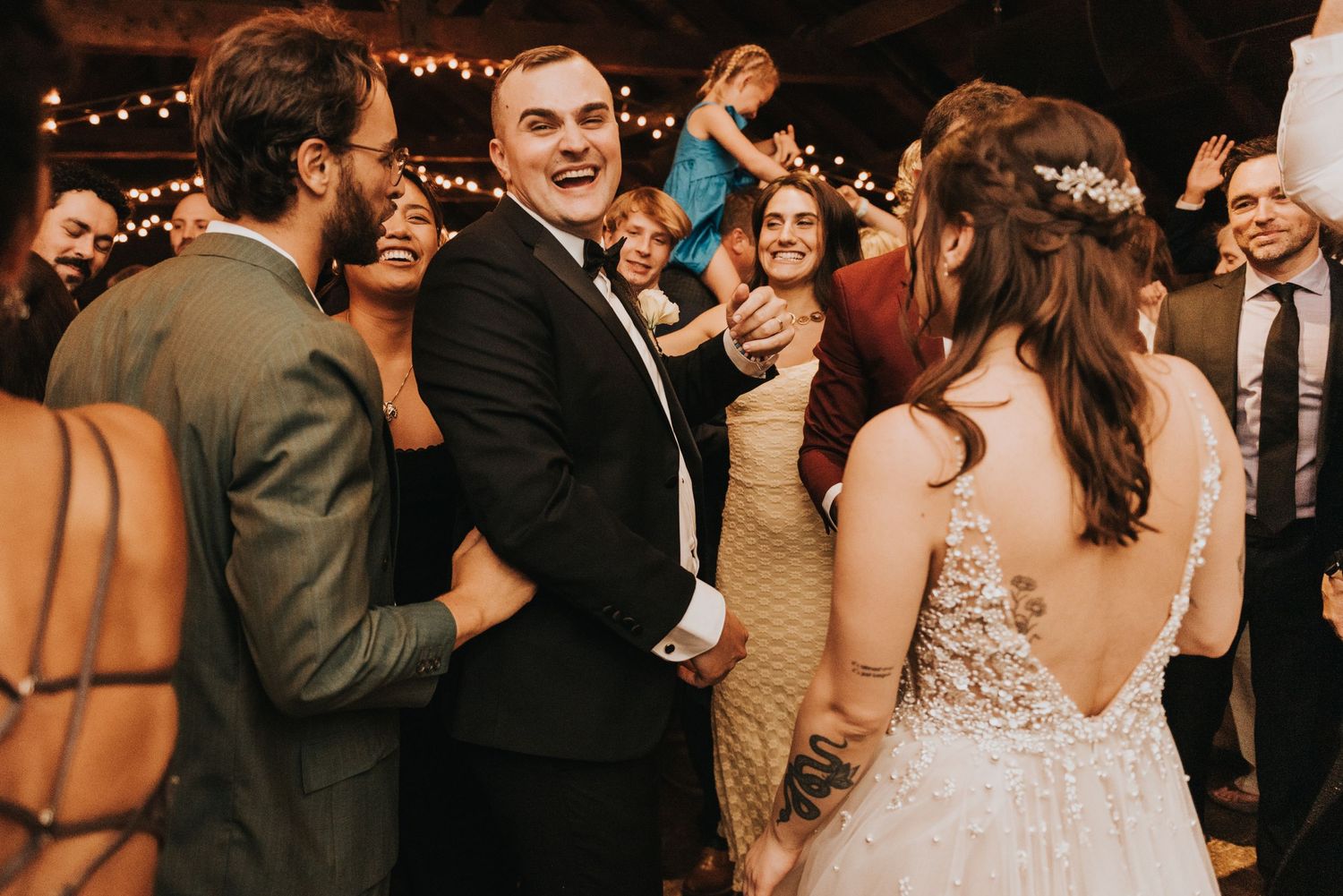Wedding guests dancing and celebrating together on the dance floor during a joyful reception party.
