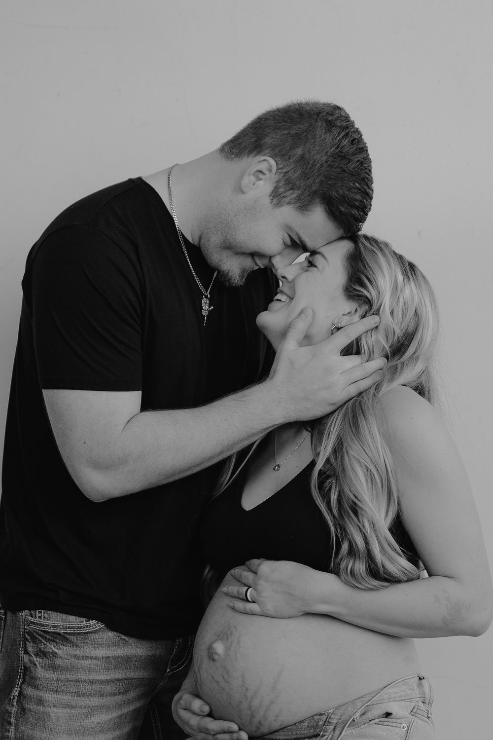 Black and white maternity photo showing a tender intimate moment between an expecting couple.