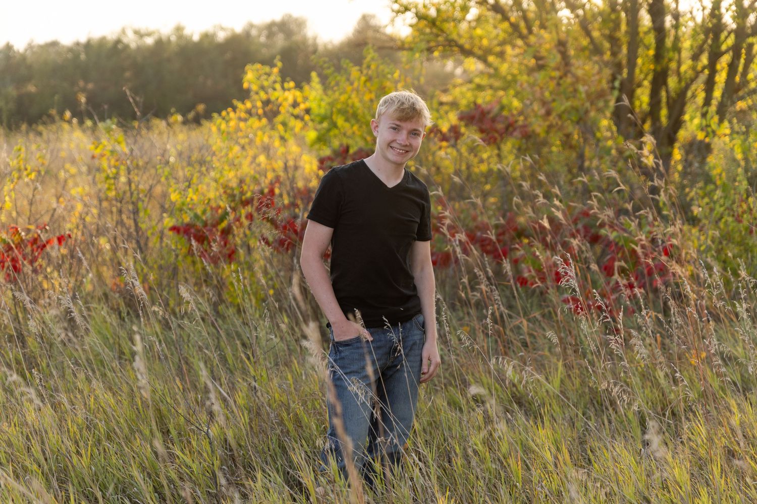 becky katzberg photography senior boy in a grassy field wearing a black shirt