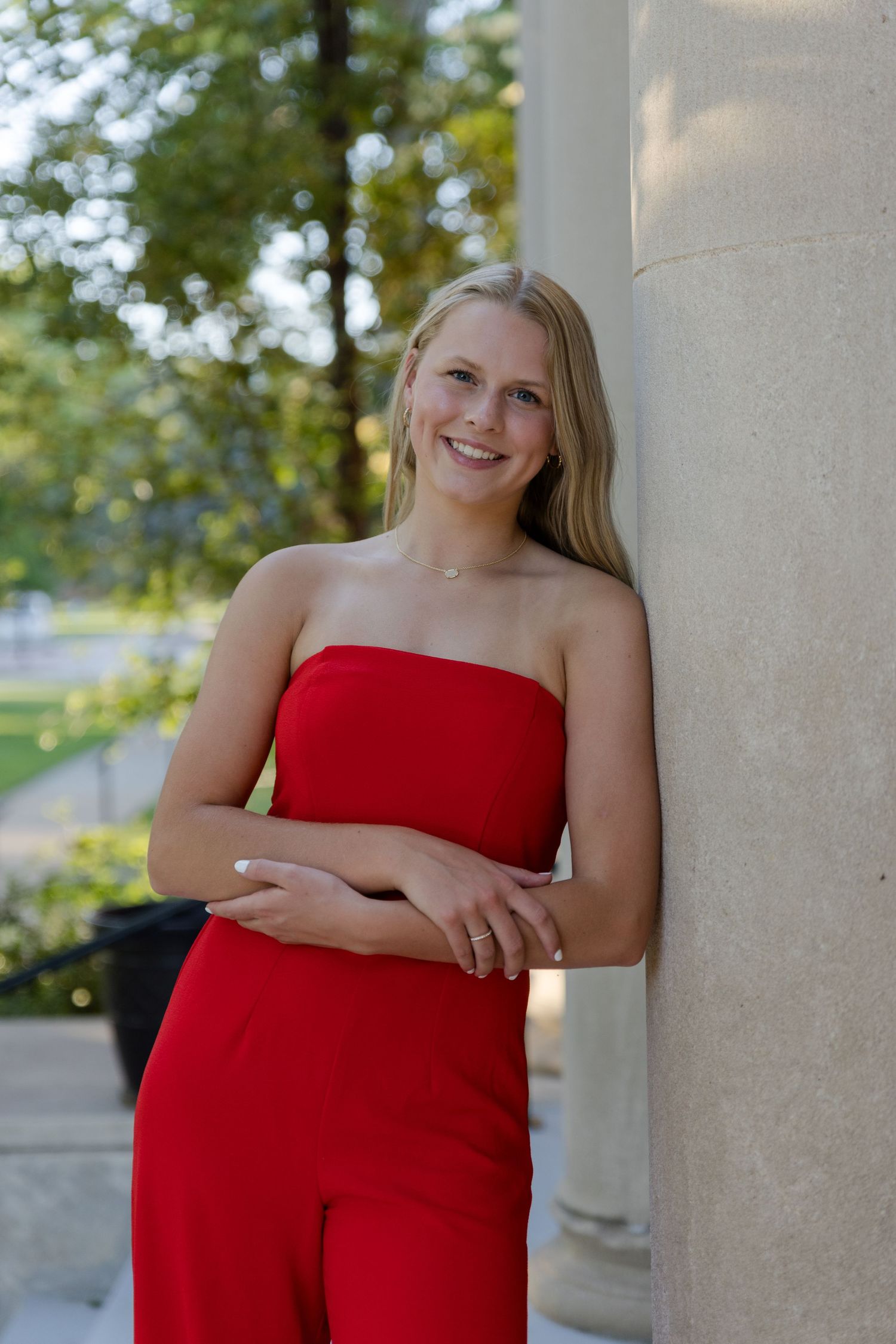 becky katzberg photography senior girl in red strapless jumpsuit leaning on a wall