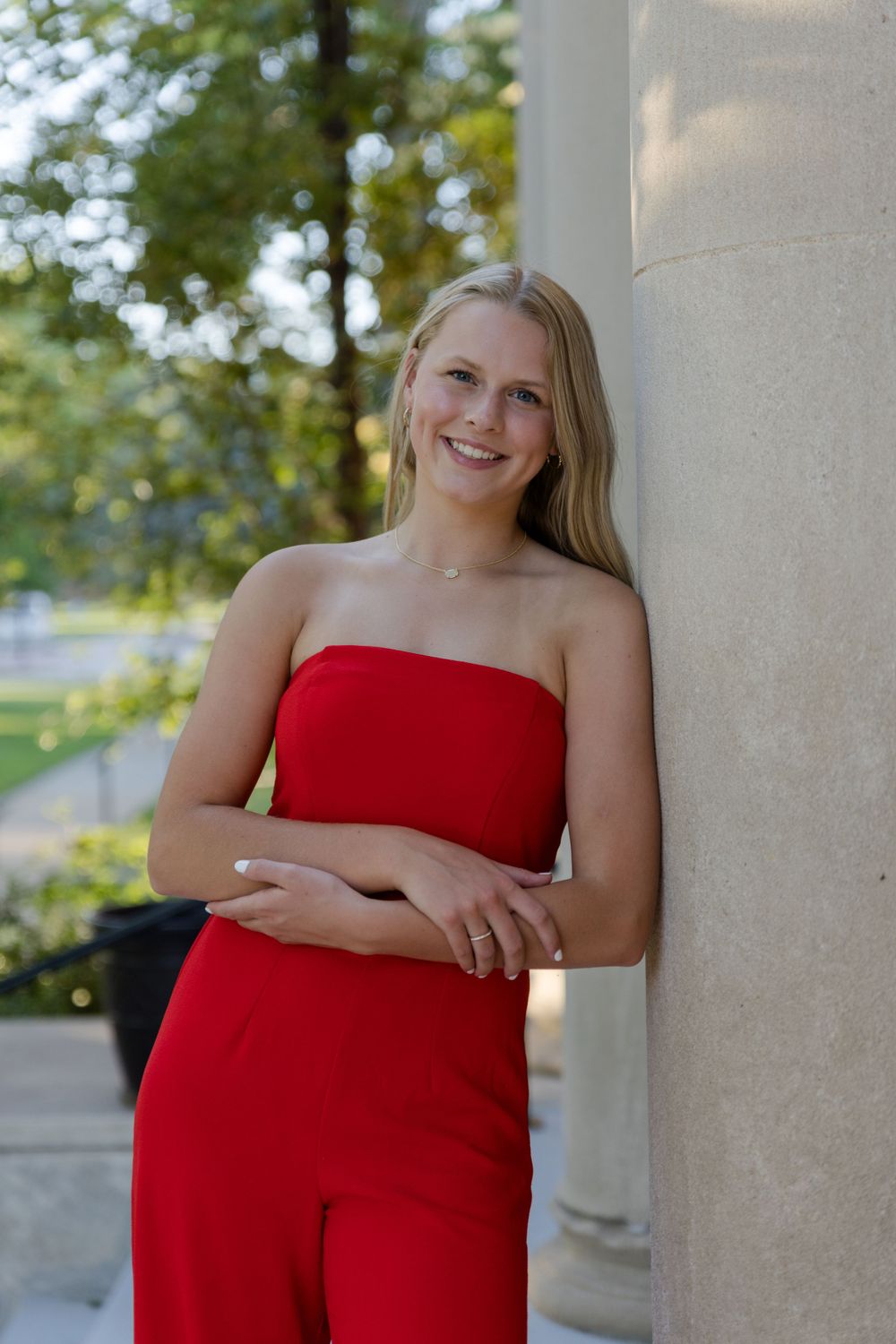 becky katzberg photography senior girl in red strapless jumpsuit leaning on a wall