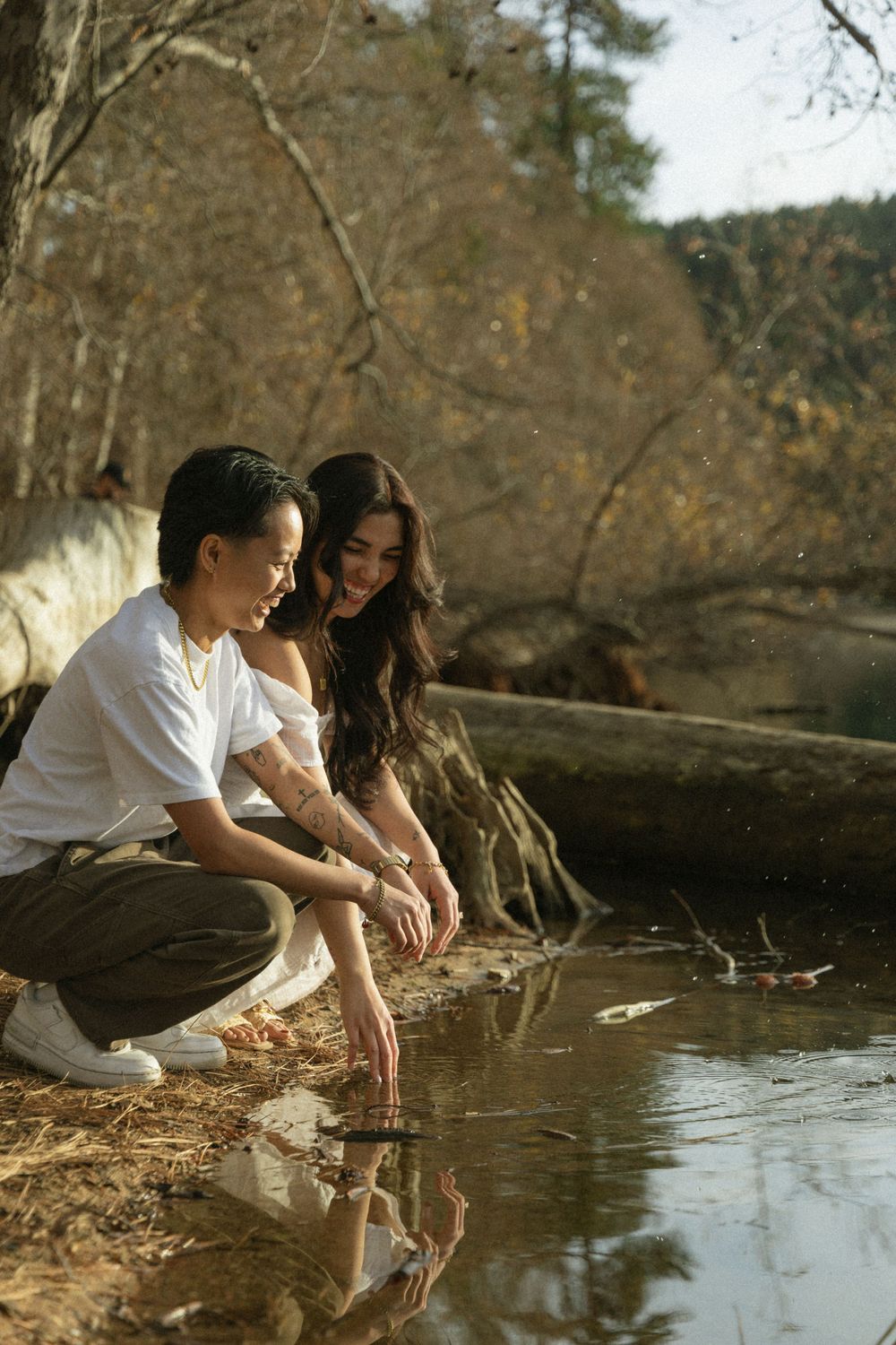 A couple spending time together by a serene pond in an autumn forest setting.