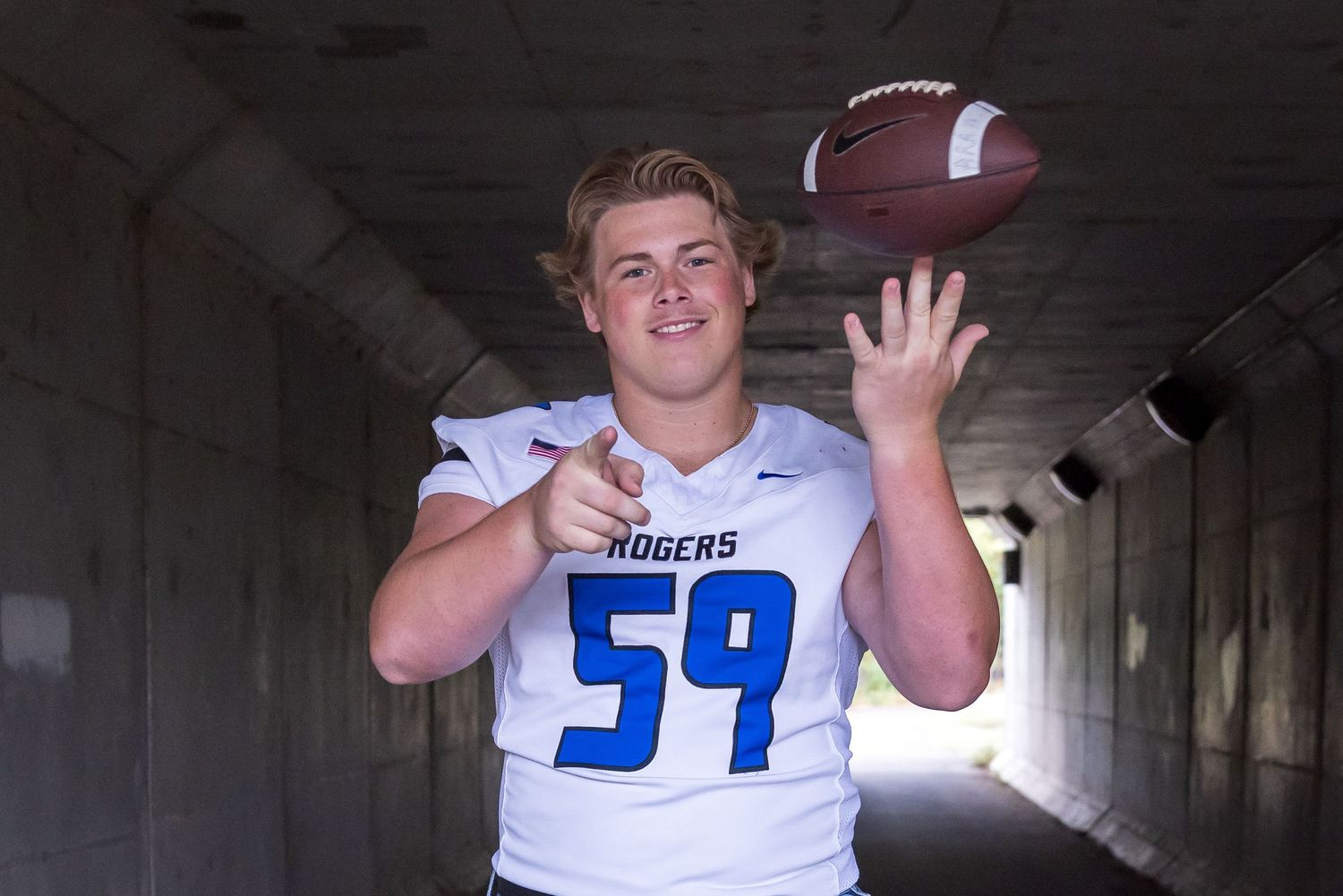 portrait of young man spinning a football on his finger and pointing at the camera