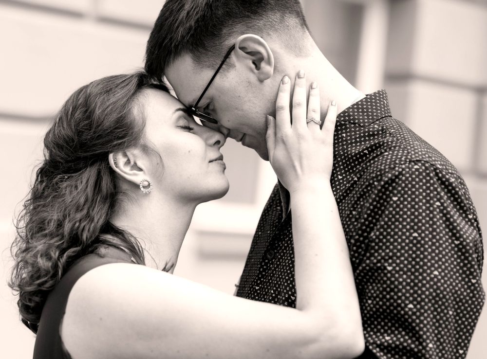 A romantic black and white portrait of two people sharing an intimate moment.