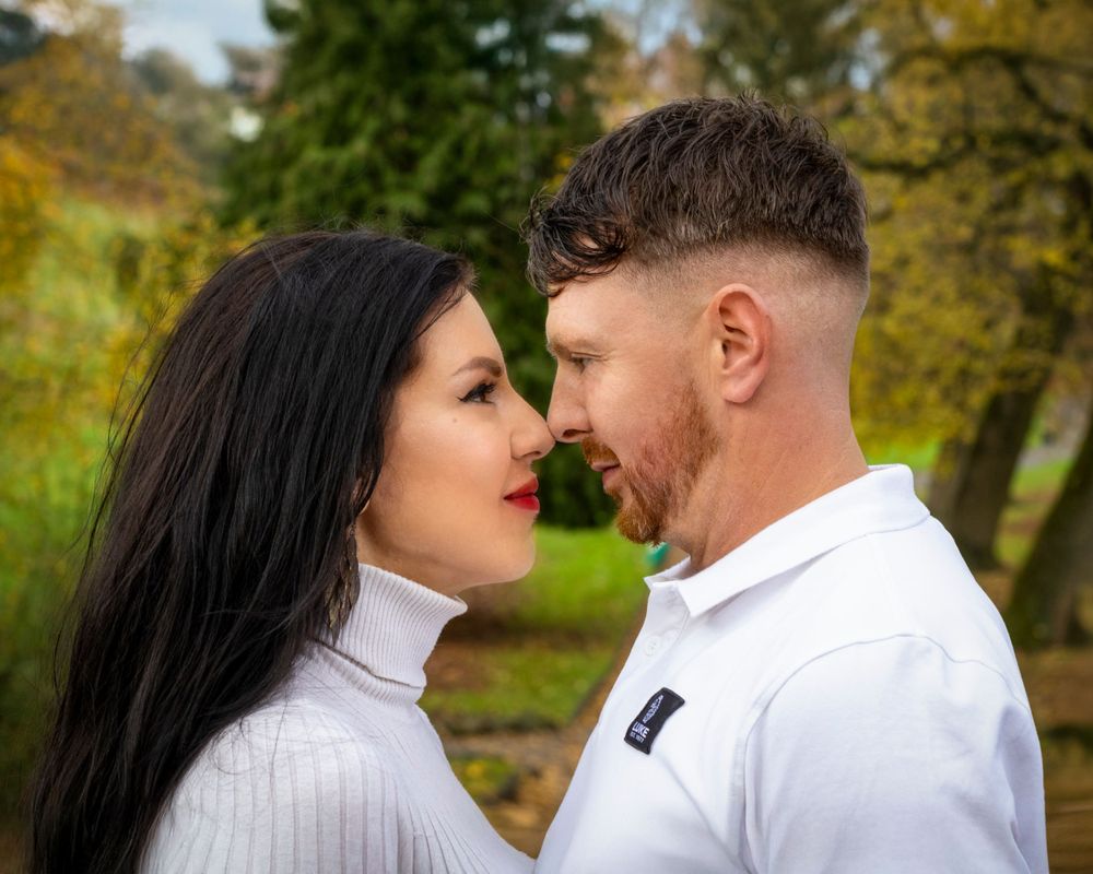 Romantic couple in white sweaters share an intimate moment in an autumn park setting. Russian speaking photographer.