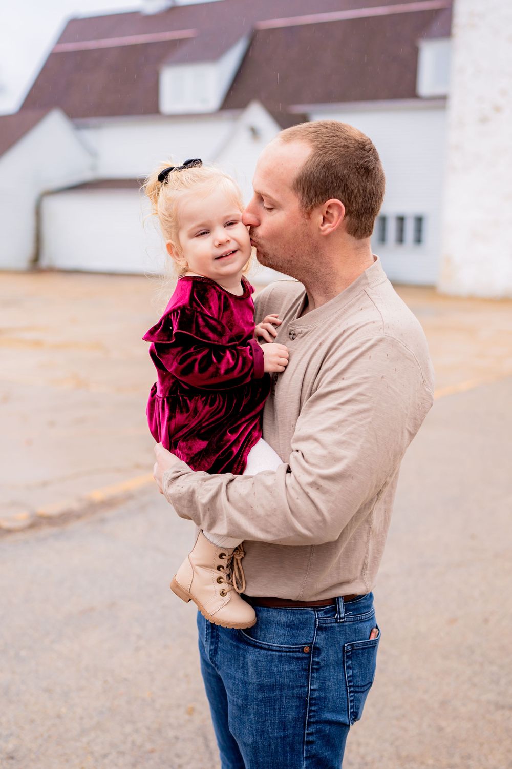 A tender moment shared outside a white building on an overcast day.