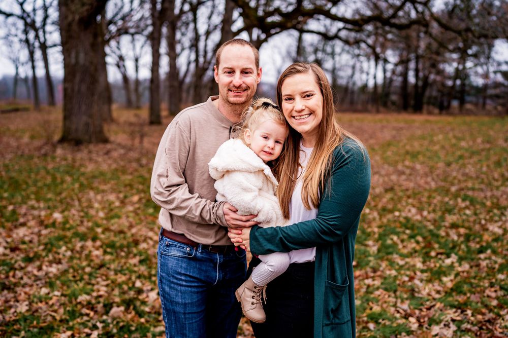 A family portrait taken in an autumn setting with fallen leaves.