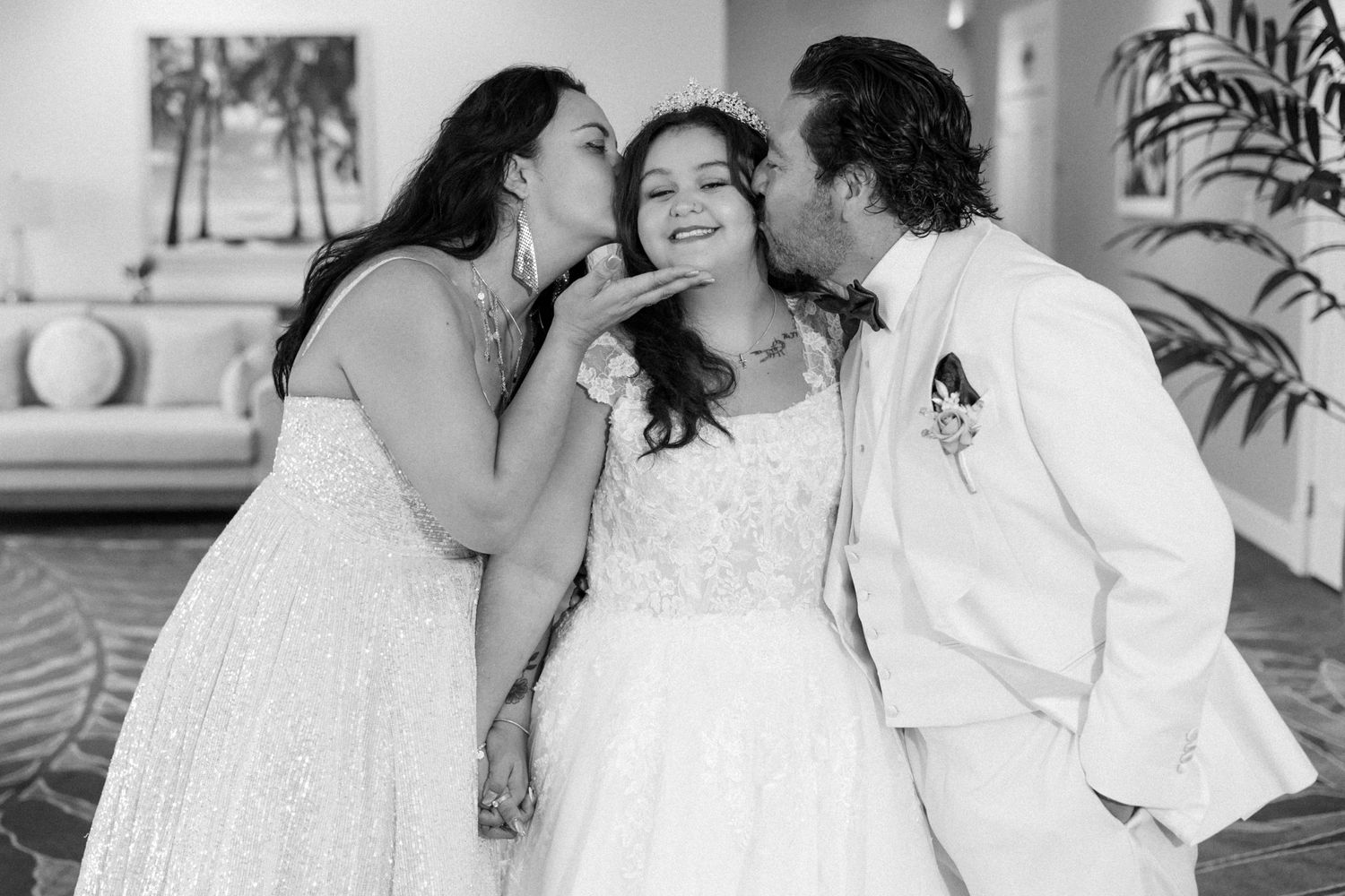 Three wedding guests share an intimate moment in black and white photography.