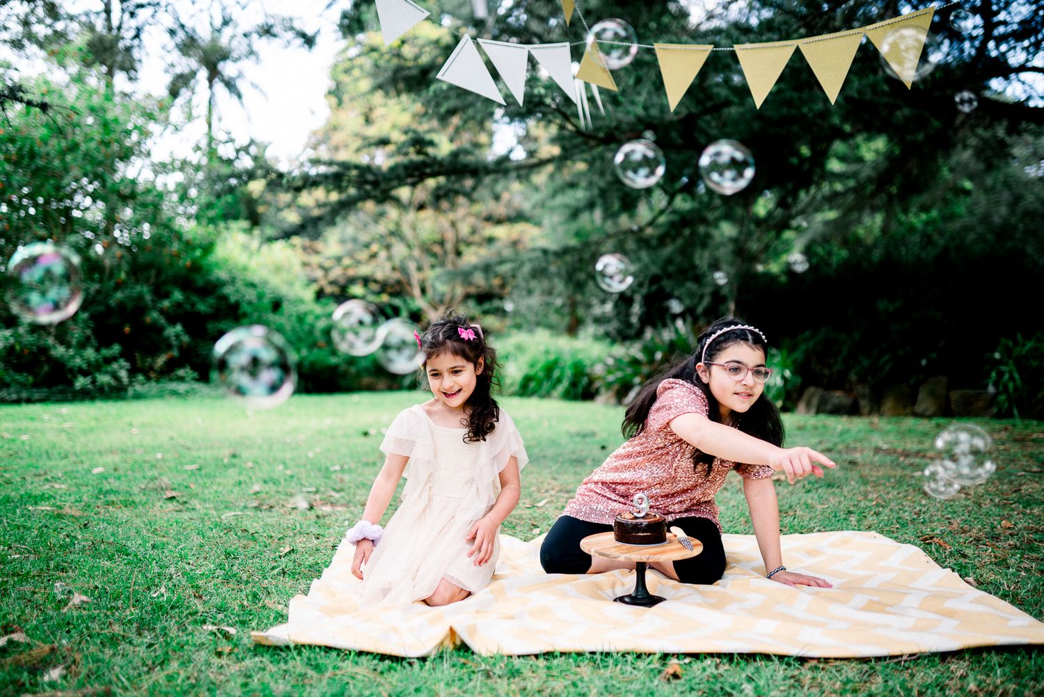 2 sisters in Melbourne's St Kilda Botanical Gardens with lush greeneries as backdrop taken by a Melbourne family photographer.