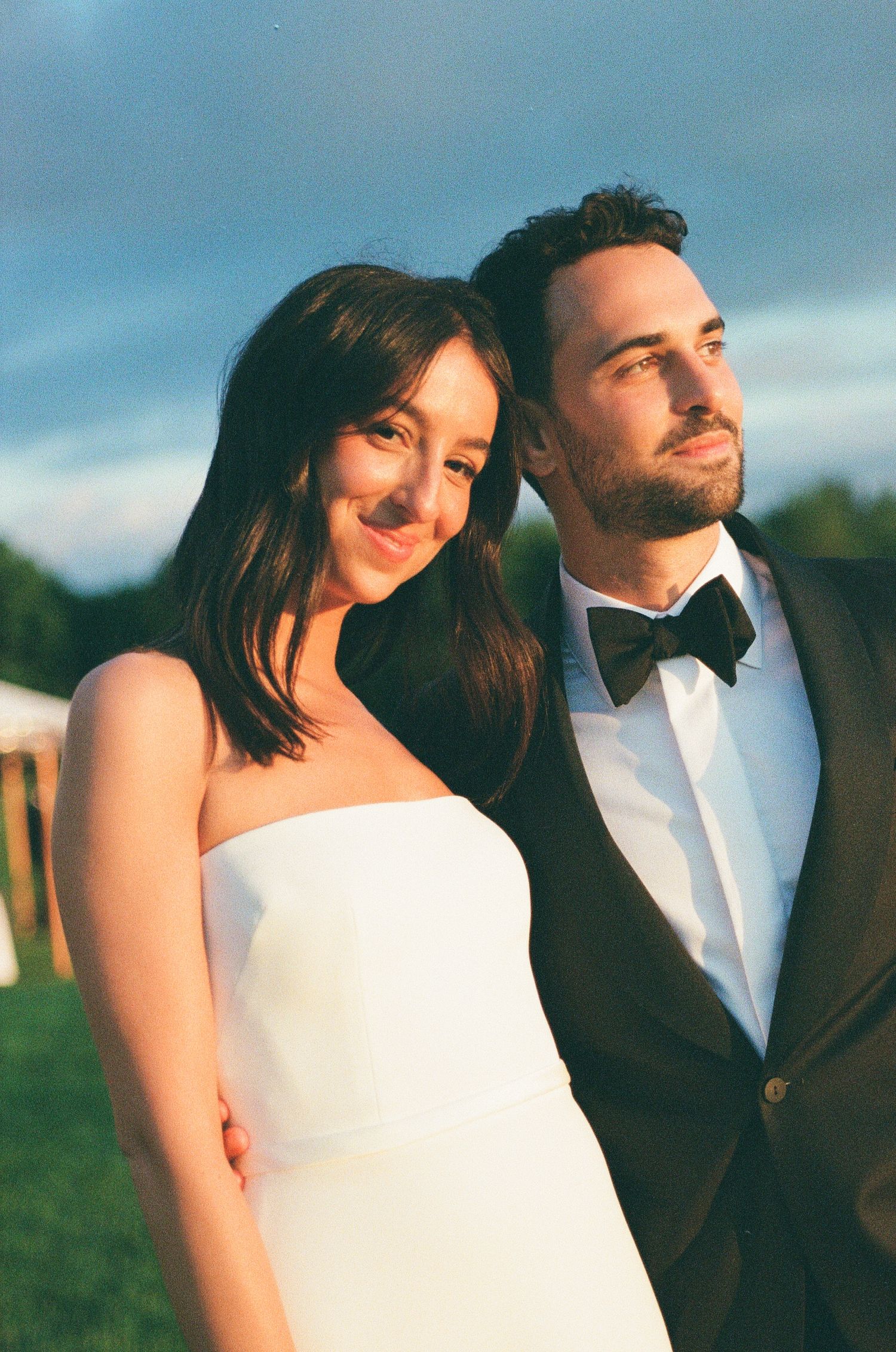 A bride and groom share an intimate moment outdoors during their wedding photoshoot at sunset.