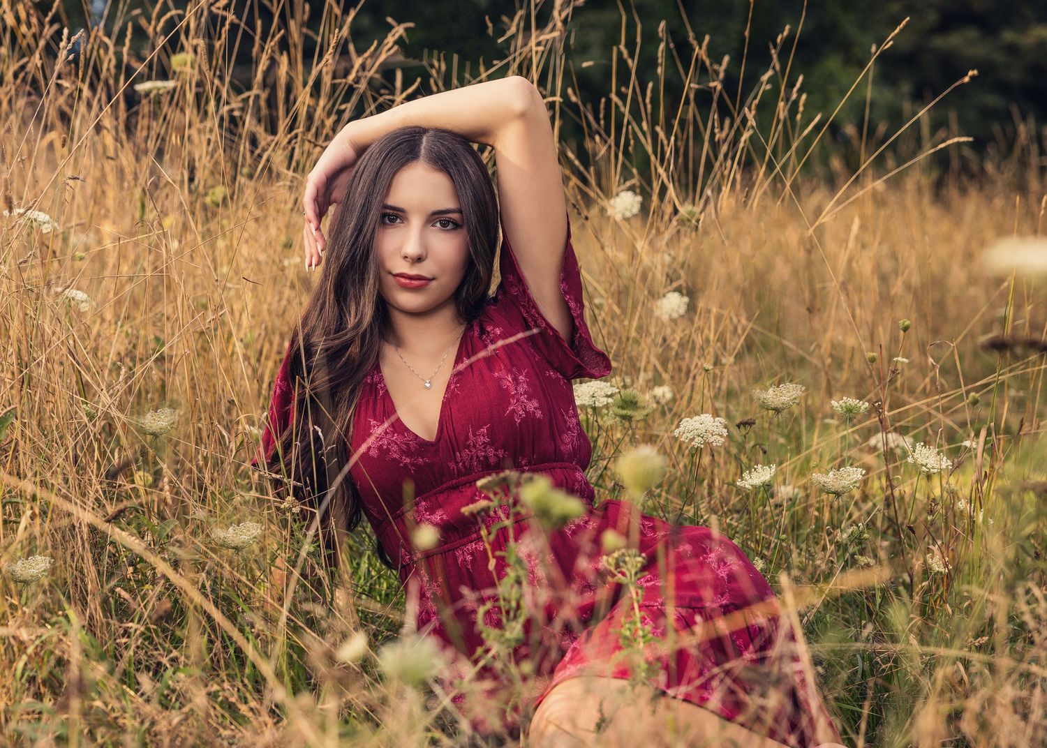 Casual outdoor portrait on wooden dock at sunset with autumn trees and water reflections in background.
