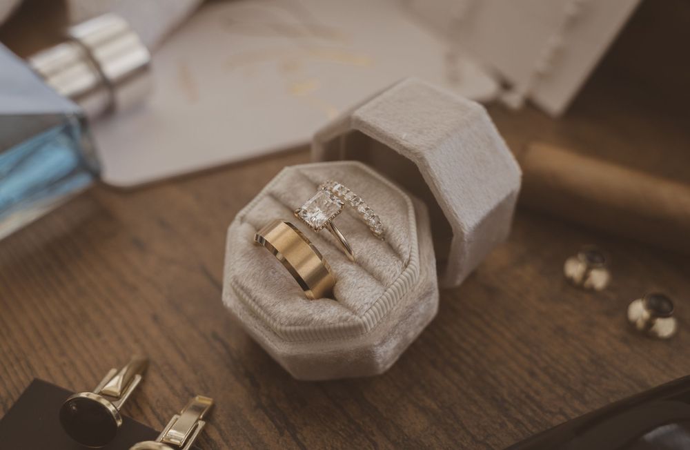 Wedding rings displayed in grey velvet ring box with rustic wooden background.