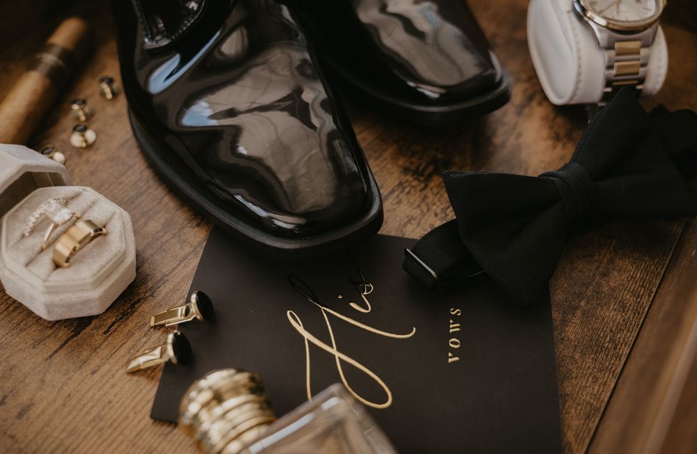 Wedding rings and jewelry details arranged on dark wooden surface.