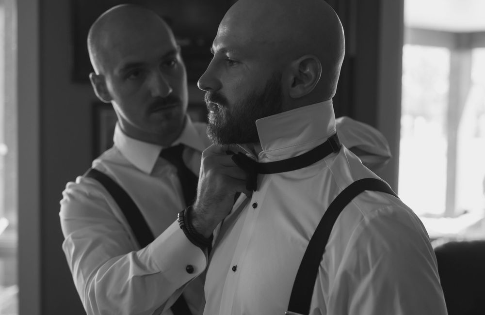 Groomsmen in formal attire preparing for wedding ceremony.