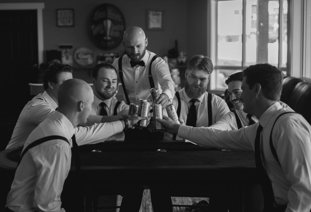 Black and white photo of groomsmen preparing in a sunlit room.