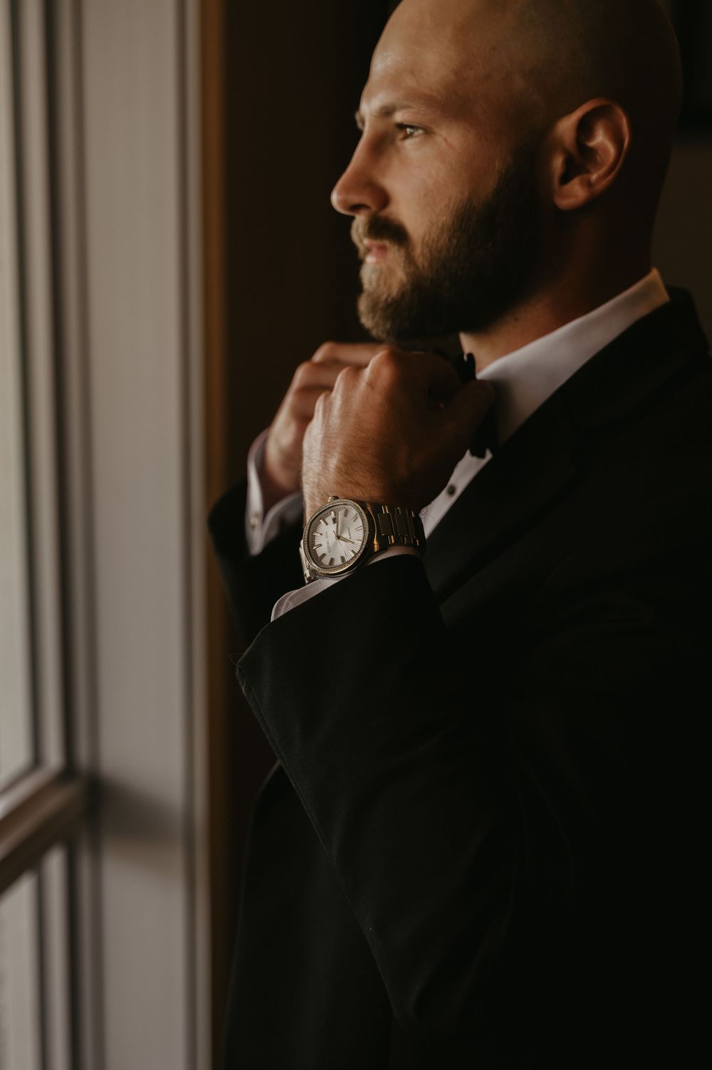 Close-up portrait of a bearded man in formal attire looking thoughtfully to the side.