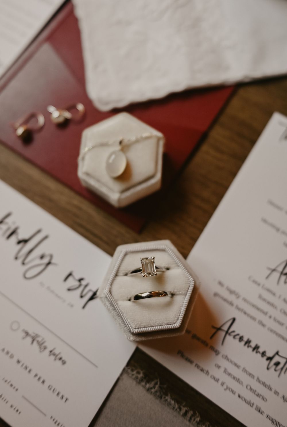 Wedding rings and invitations arranged artistically on a wooden surface.
