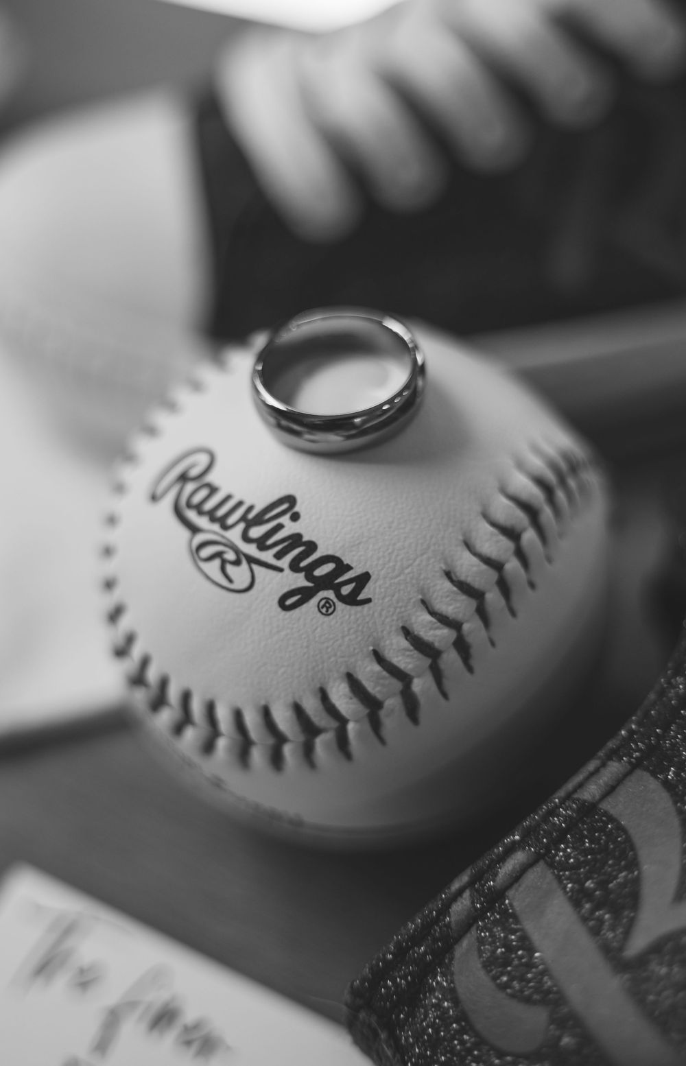 Close-up black and white detail shot of a Rawlings baseball with stitching visible.