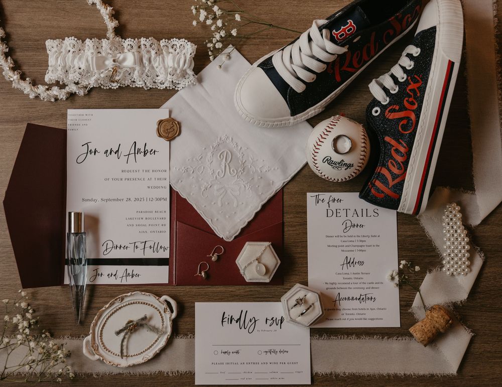 Wedding stationery and invitation suite featuring elegant calligraphy and floral designs laid out on a wooden surface.