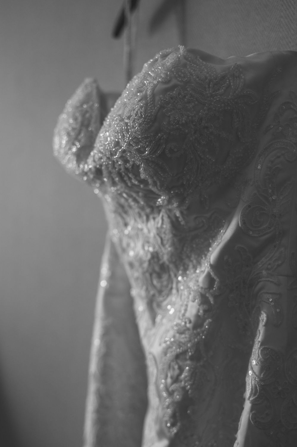 Close-up details of intricate lace and beadwork on delicate fabric in black and white.