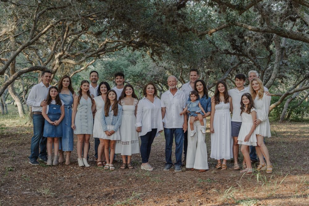 Extended family portrait with multiple generations wearing coordinated white and blue clothing.