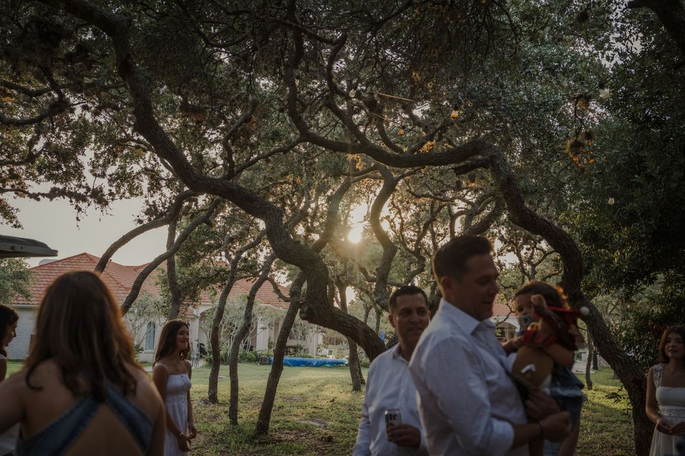 Candid family moments captured under large oak trees in a park setting.