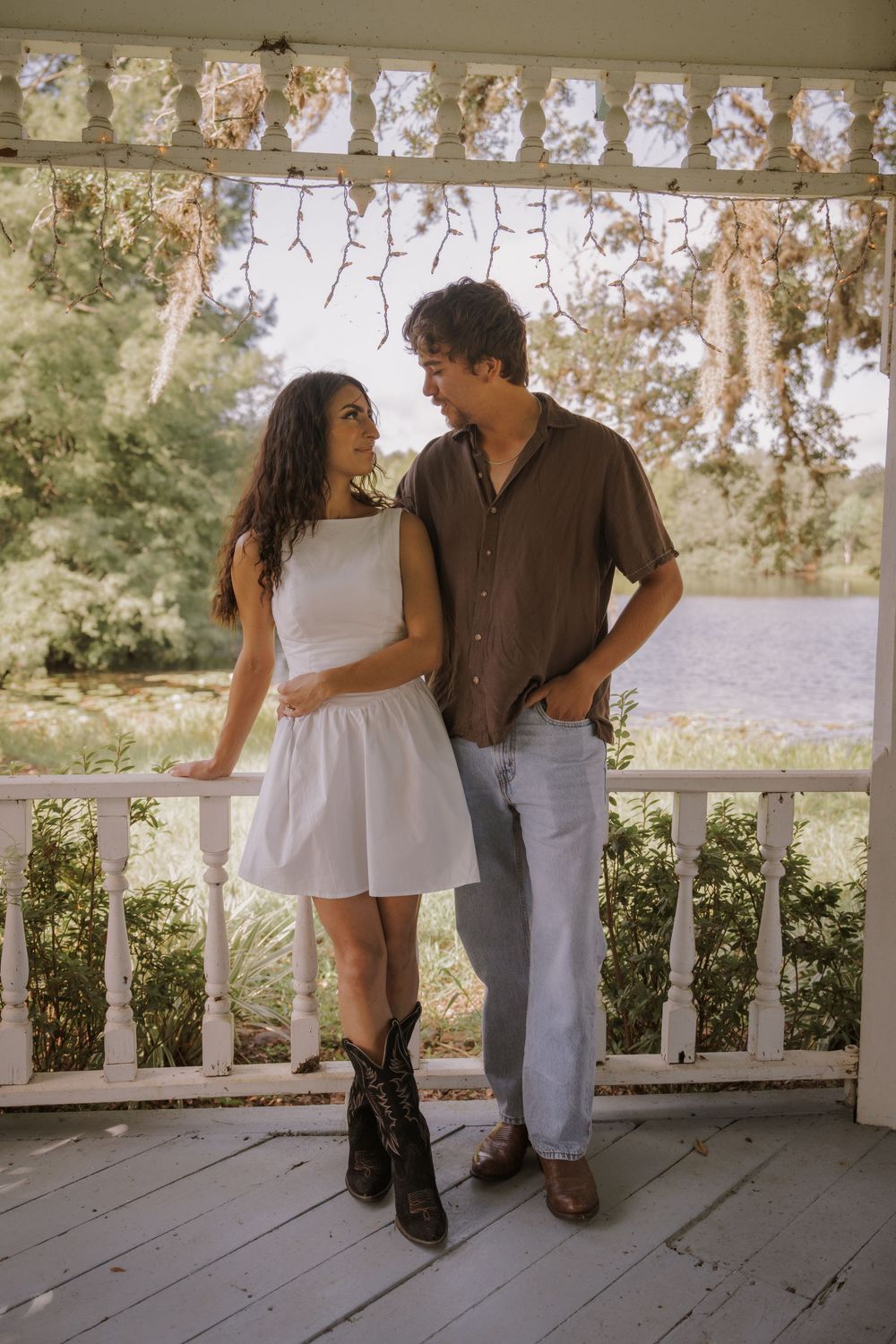 Couple sharing sweet moments on a white porch with scenic views.