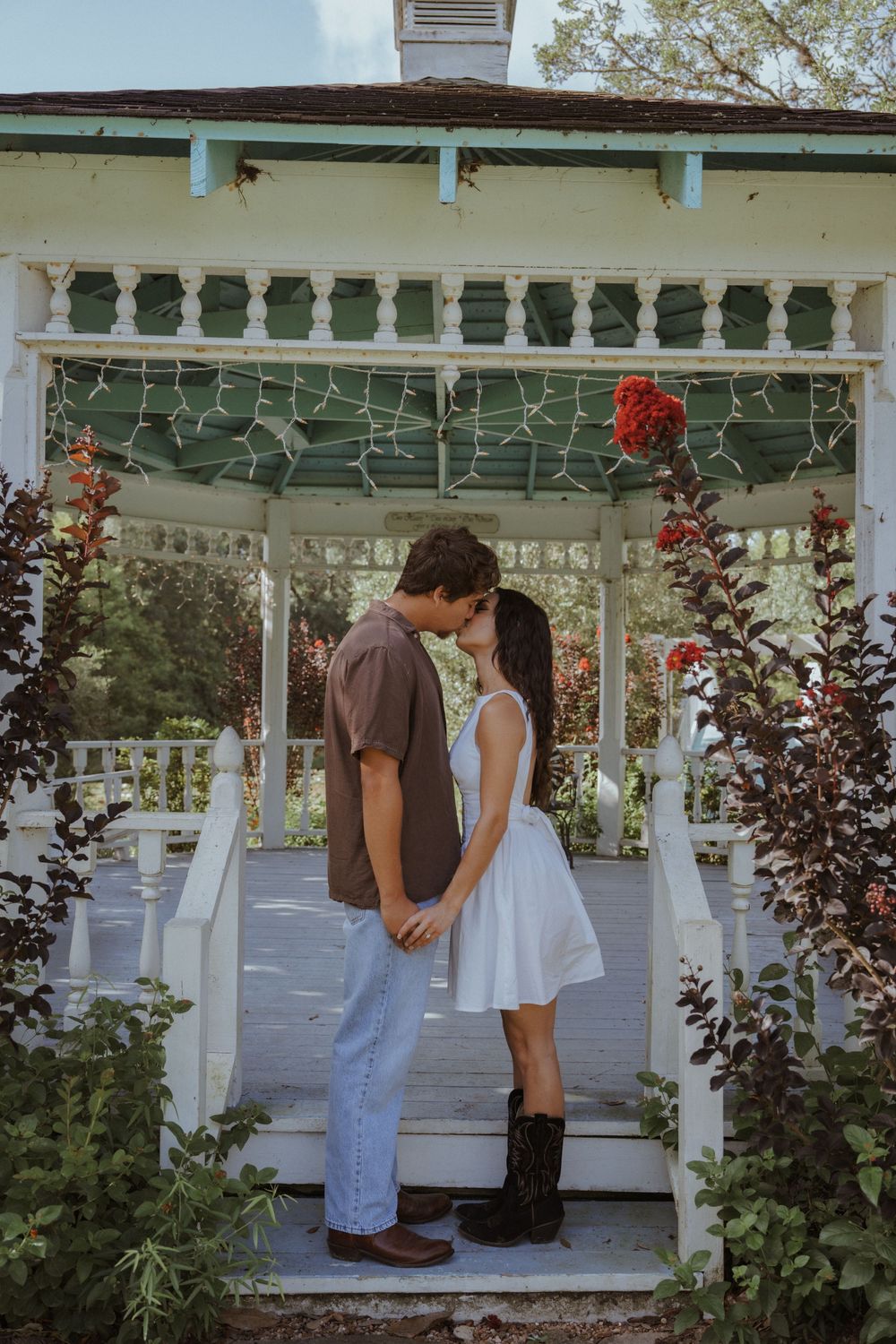 Romantic scene in a white gazebo surrounded by blooming red roses.