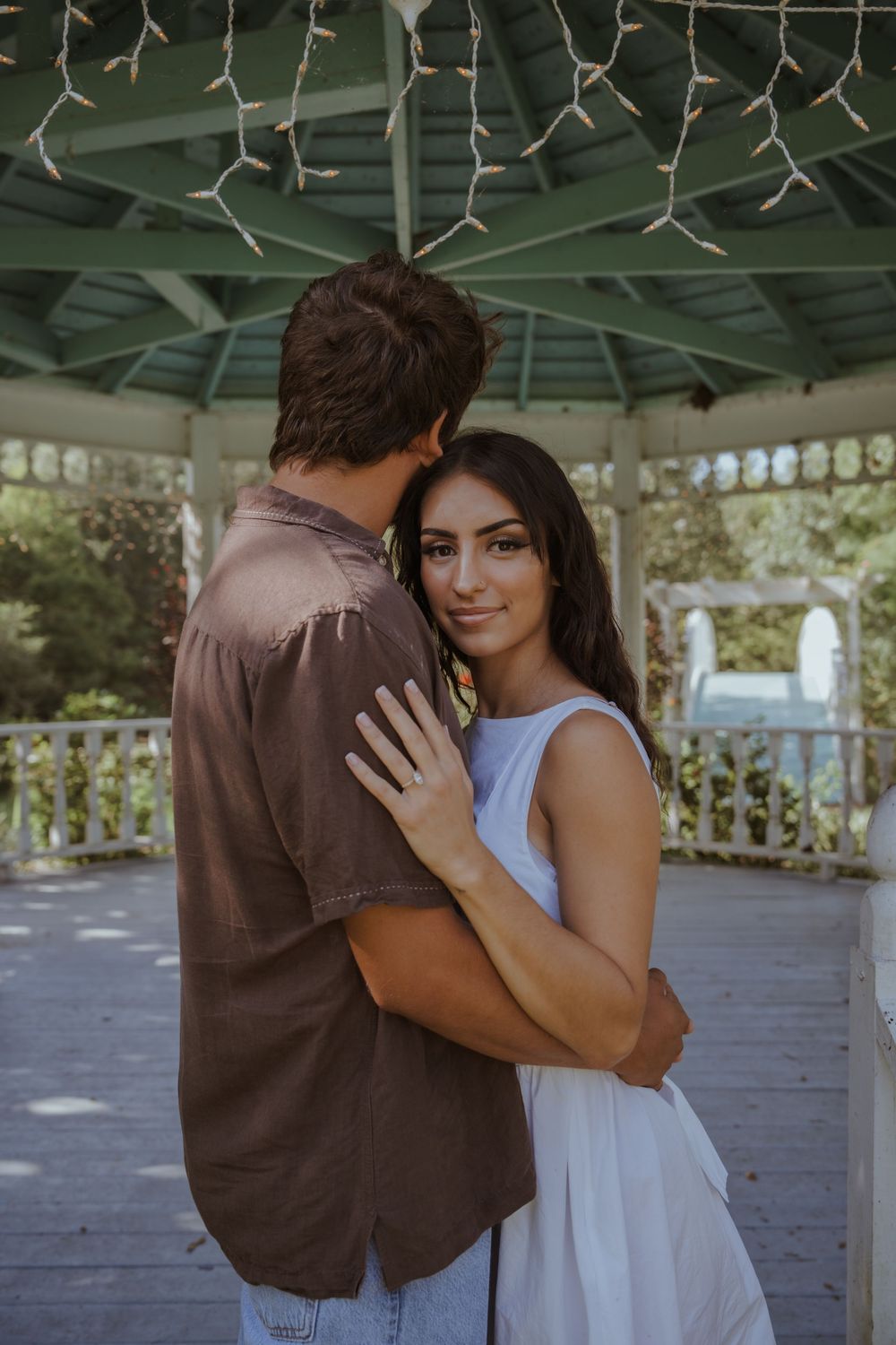 Tender embrace captured in a gazebo decorated with string lights.