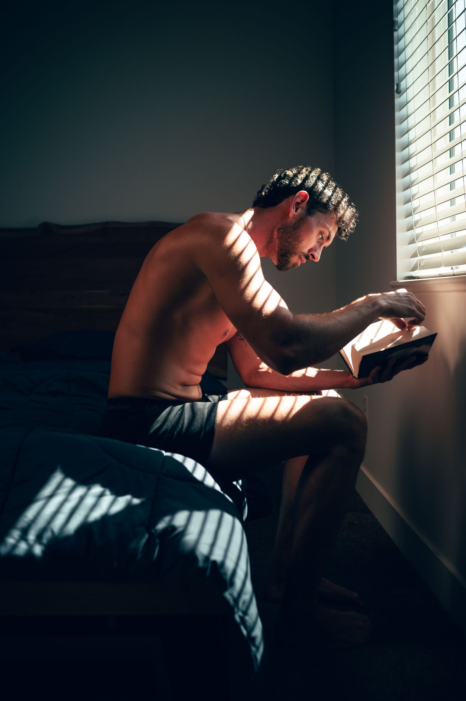 Utah male boudoir photography by Carl James Photography in Salt Lake City, featuring masculine posing and man reading a book.