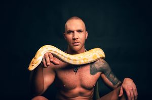 Utah male boudoir and fitness photography by Carl James Photography in Salt Lake City, featuring man posing with a yellow python snake.