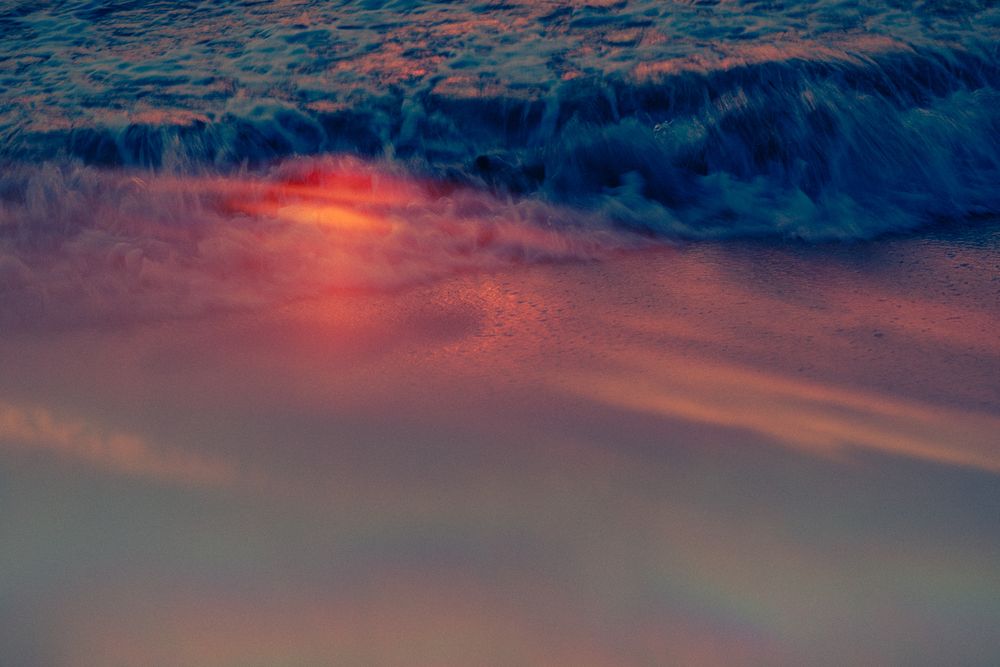 Dramatic sunset sky with dark blue clouds reflecting vibrant orange and pink hues in a dreamy atmospheric scene.