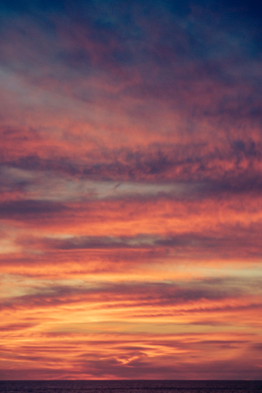 A series of vibrant sunset photos showing dramatic orange and pink clouds stretching across the darkening horizon.