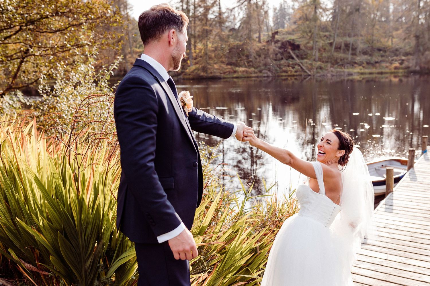 Romantic wedding couple shares intimate moments in a scenic outdoor setting with golden autumn foliage and a lake backdrop at Gilpin Hotel .