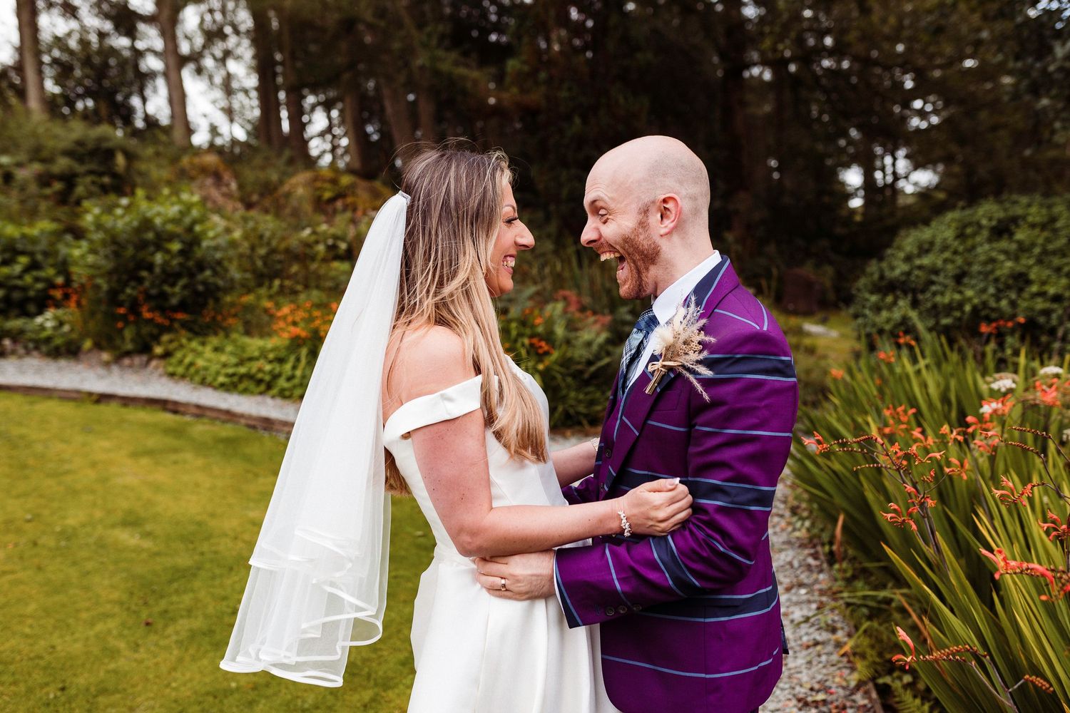 Bride and groom laugh at each other in the Gilpin Hotel and Lake house's woodland edges